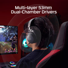 Person wearing a gaming headset with text about multi-layer 53mm dual-chamber drivers, sitting in front of a computer screen.